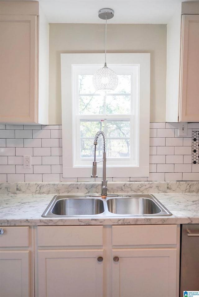 kitchen with pendant lighting, decorative backsplash, sink, and white cabinetry