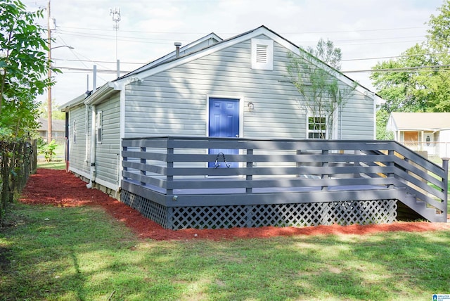 back of property featuring a wooden deck and a lawn