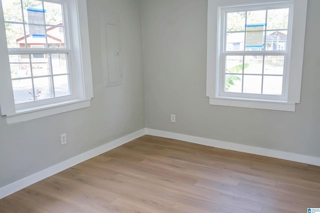 spare room featuring electric panel and light hardwood / wood-style floors