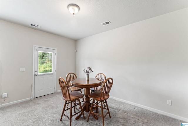 dining space featuring baseboards and light carpet