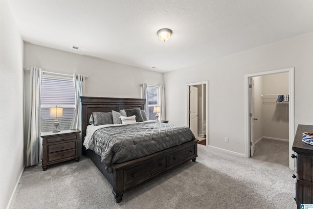 bedroom featuring carpet floors, baseboards, a spacious closet, and ensuite bathroom