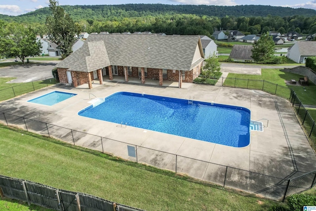 view of pool with a patio and a view of trees