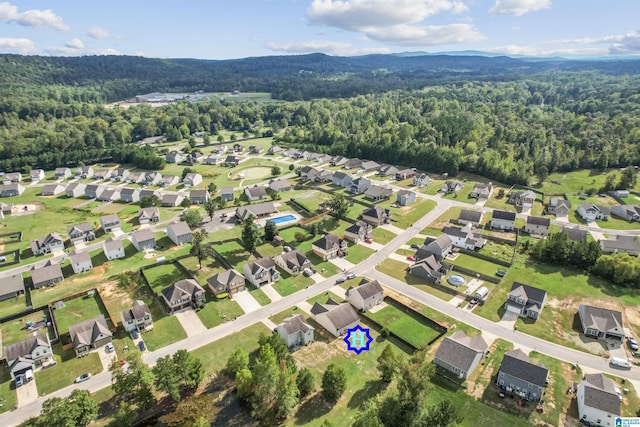 aerial view of property's location featuring a forest, nearby suburban area, and a mountain backdrop