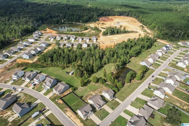 view of property location with a heavily wooded area, a large body of water, and nearby suburban area