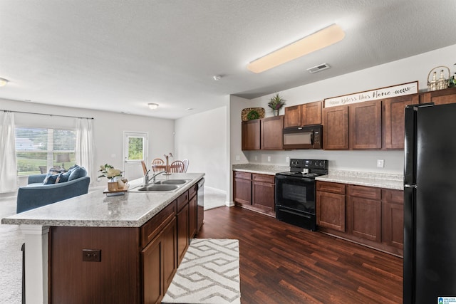 kitchen with black appliances, a sink, dark wood finished floors, light countertops, and open floor plan