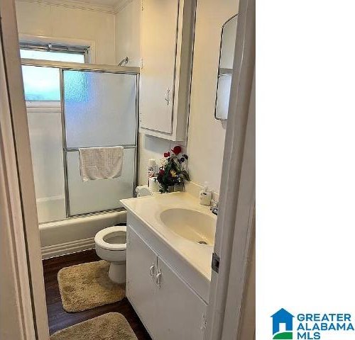 full bathroom featuring enclosed tub / shower combo, vanity, hardwood / wood-style floors, and toilet