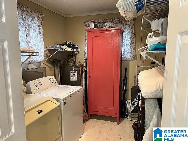 laundry room with electric water heater, crown molding, and washing machine and clothes dryer