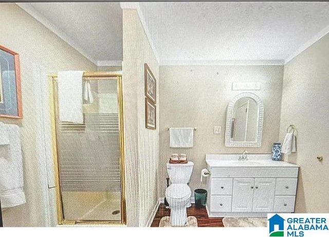 bathroom with ornamental molding, vanity, toilet, and an enclosed shower