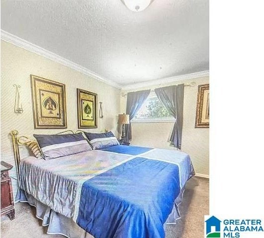 bedroom with a textured ceiling, ornamental molding, and carpet