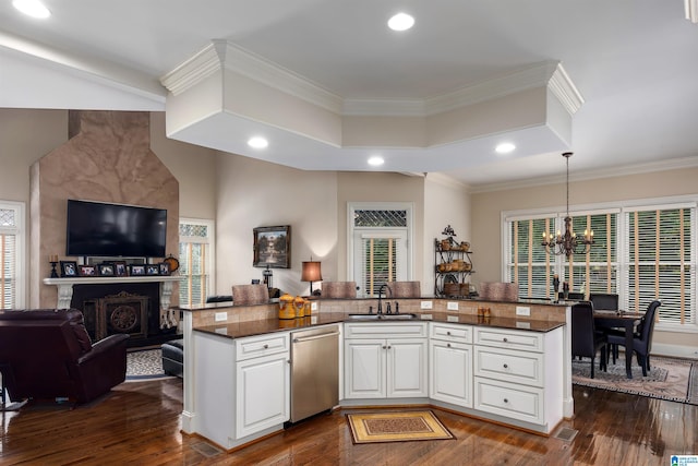 kitchen with white cabinets, hanging light fixtures, stainless steel dishwasher, dark hardwood / wood-style floors, and sink