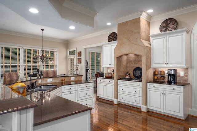 kitchen featuring sink, kitchen peninsula, decorative light fixtures, white cabinets, and dark wood-type flooring