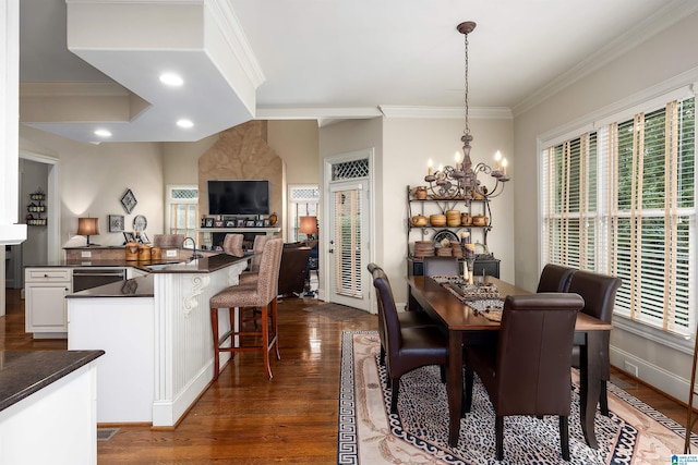 dining room with sink, a notable chandelier, ornamental molding, and dark hardwood / wood-style flooring