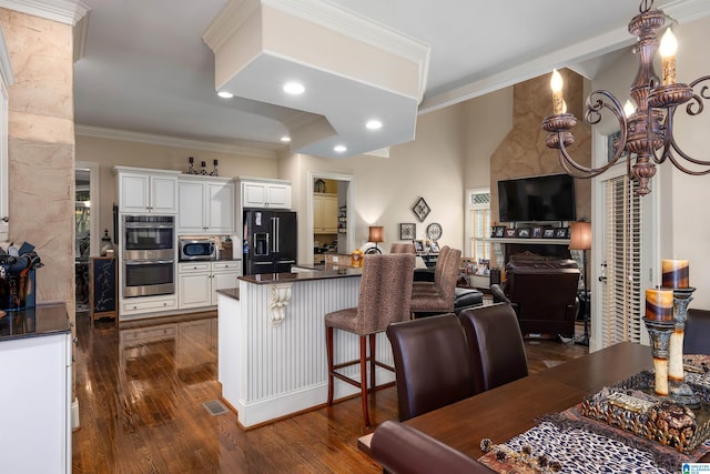 kitchen with white cabinets, dark hardwood / wood-style flooring, a breakfast bar area, crown molding, and stainless steel appliances