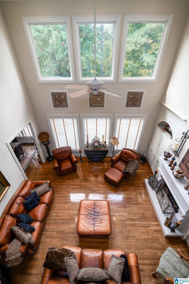 living room featuring ceiling fan, a towering ceiling, and wood-type flooring