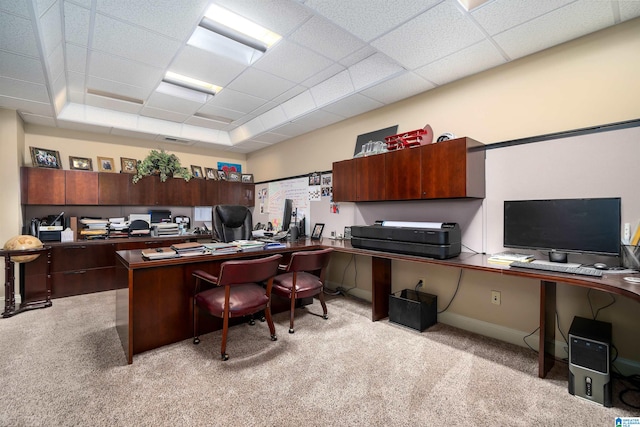 carpeted home office with built in desk and a paneled ceiling