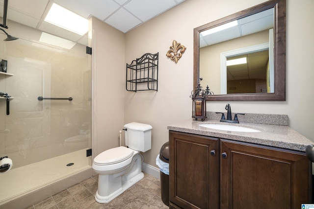 bathroom with vanity, toilet, a shower, and a drop ceiling