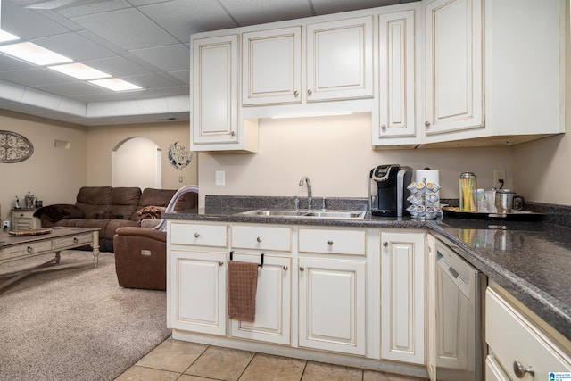 kitchen with light carpet, sink, stainless steel dishwasher, white cabinetry, and a paneled ceiling