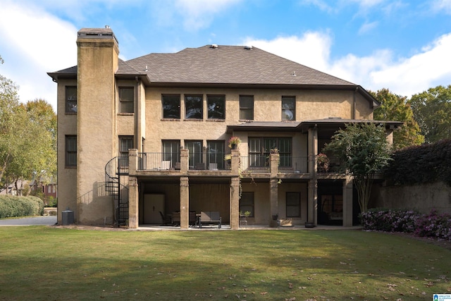 back of house with a balcony, a patio, and a lawn