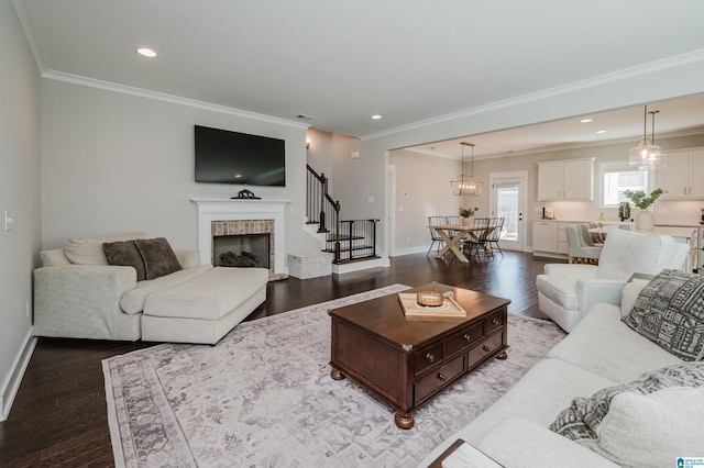 living room with hardwood / wood-style flooring, crown molding, and a tiled fireplace