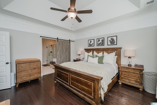 bedroom featuring ensuite bathroom, dark wood-type flooring, ceiling fan, and a barn door