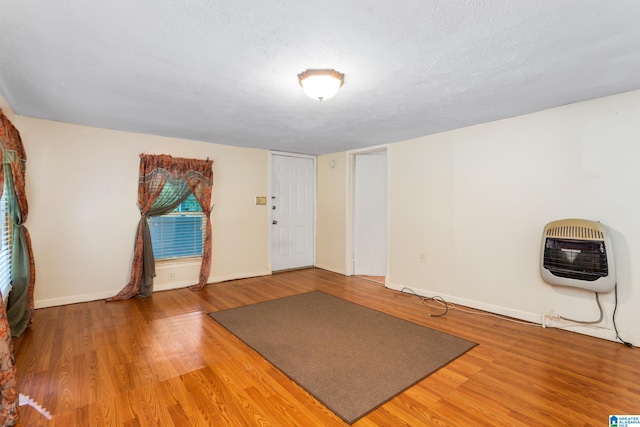 exercise area featuring heating unit, a textured ceiling, and hardwood / wood-style flooring