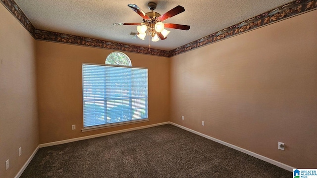 spare room featuring dark colored carpet, a wealth of natural light, and ceiling fan