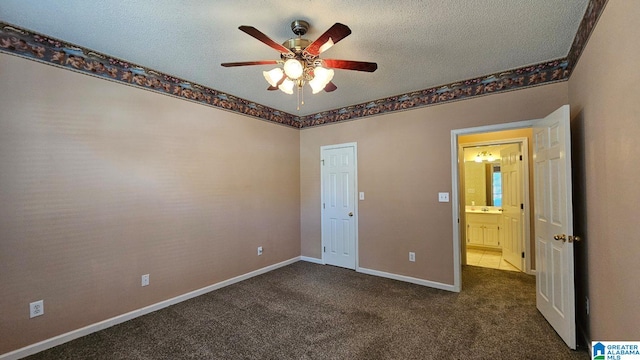 unfurnished bedroom featuring ceiling fan, dark carpet, and a textured ceiling