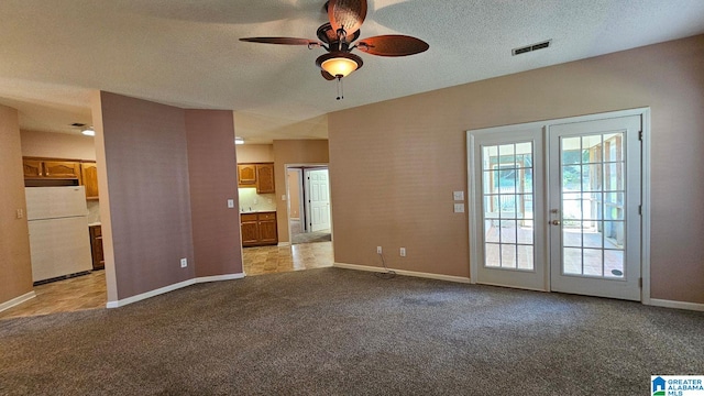 unfurnished living room with ceiling fan, light colored carpet, a textured ceiling, and french doors