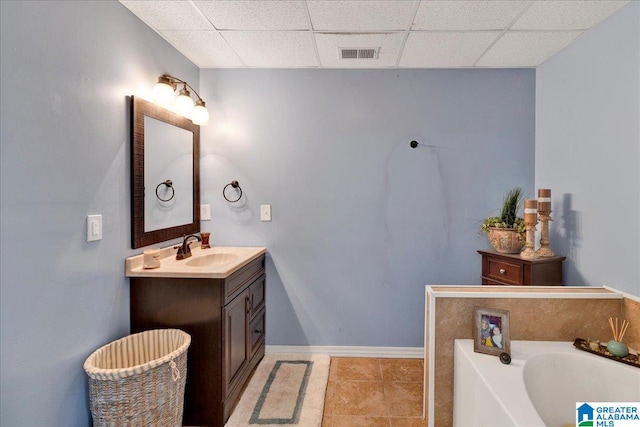 bathroom with vanity, a bathing tub, a paneled ceiling, and tile patterned flooring