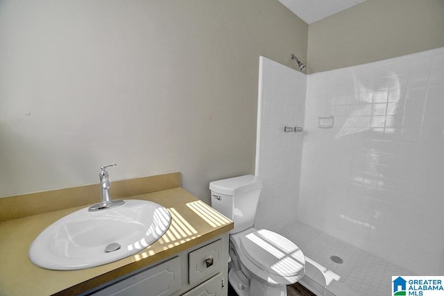 bathroom with vanity, tiled shower, and toilet