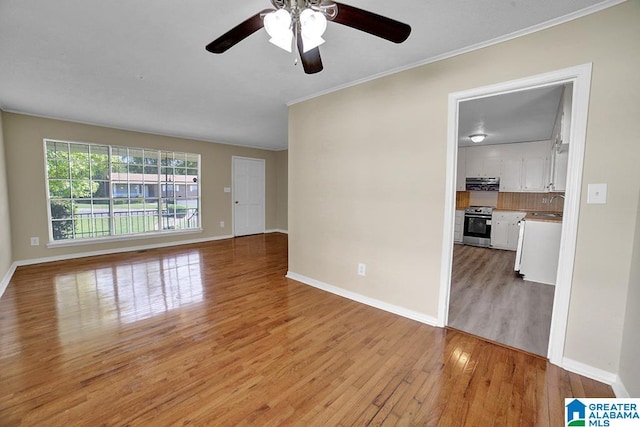 empty room featuring ceiling fan, ornamental molding, light hardwood / wood-style flooring, and sink