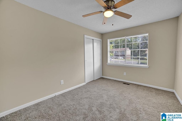 unfurnished bedroom featuring a textured ceiling, ceiling fan, a closet, and carpet flooring