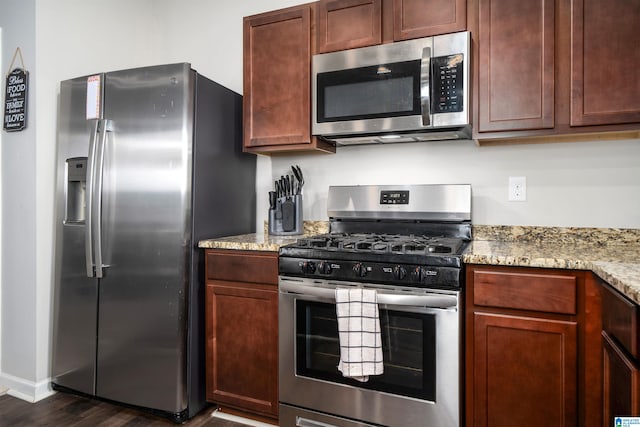 kitchen featuring dark hardwood / wood-style flooring, light stone counters, and appliances with stainless steel finishes