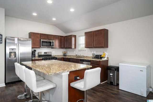 kitchen with a center island, stainless steel appliances, dark hardwood / wood-style floors, lofted ceiling, and a breakfast bar