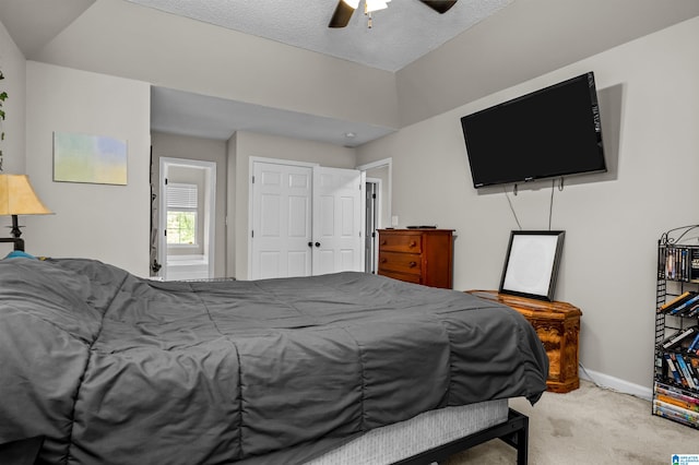 bedroom featuring light carpet, a textured ceiling, and ceiling fan