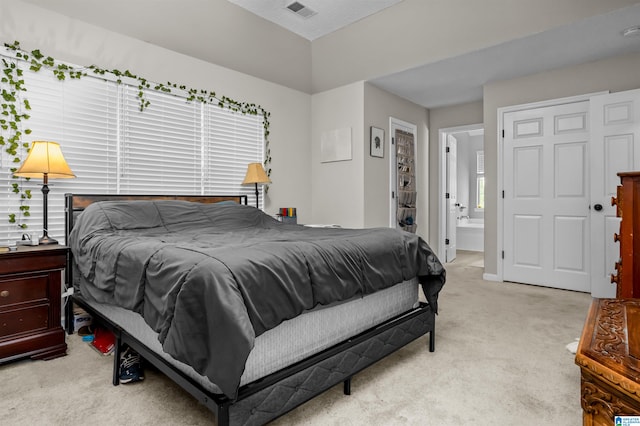 bedroom with light carpet and connected bathroom