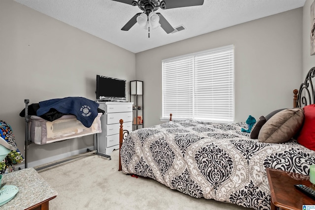 bedroom featuring ceiling fan, a textured ceiling, and carpet