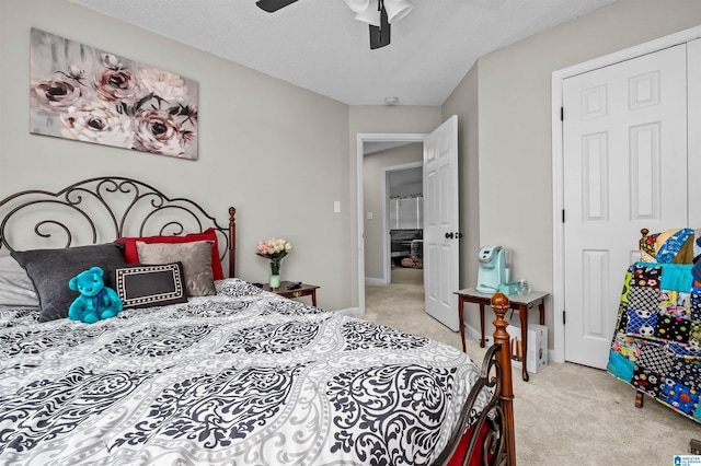 bedroom featuring a textured ceiling, ceiling fan, a closet, and light colored carpet