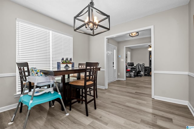 dining room with hardwood / wood-style flooring, ceiling fan with notable chandelier, and a textured ceiling