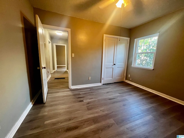 unfurnished bedroom featuring ceiling fan and dark hardwood / wood-style floors