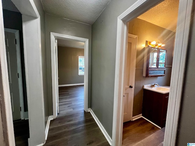 hall featuring dark wood-type flooring, sink, and a textured ceiling