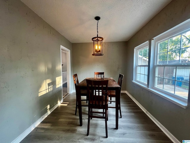 dining space with a textured ceiling, a notable chandelier, and dark hardwood / wood-style flooring