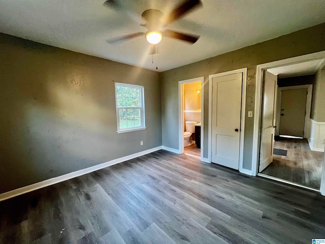 unfurnished bedroom featuring ceiling fan, connected bathroom, and dark hardwood / wood-style flooring