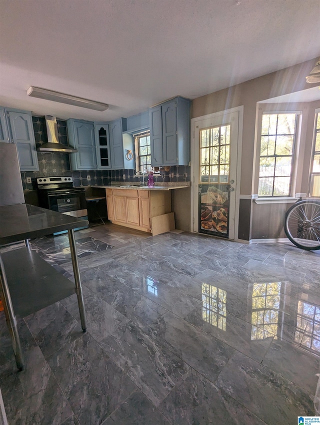 kitchen with electric stove, backsplash, sink, and wall chimney range hood