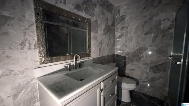 bathroom featuring tile walls, vanity, and toilet