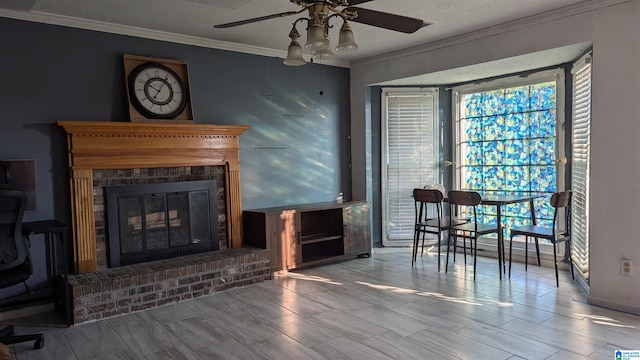 living room featuring ceiling fan, a textured ceiling, a fireplace, and crown molding