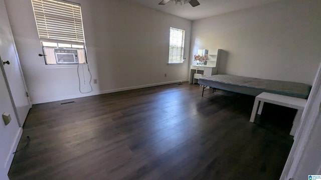 bedroom featuring cooling unit, dark hardwood / wood-style floors, multiple windows, and ceiling fan