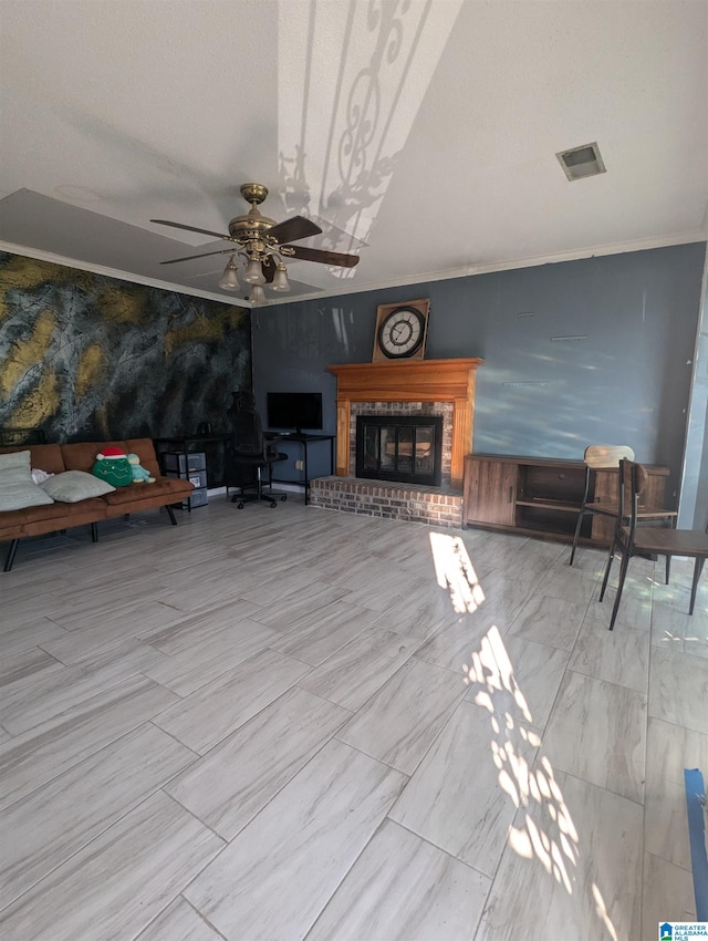 unfurnished living room featuring a brick fireplace, crown molding, and ceiling fan