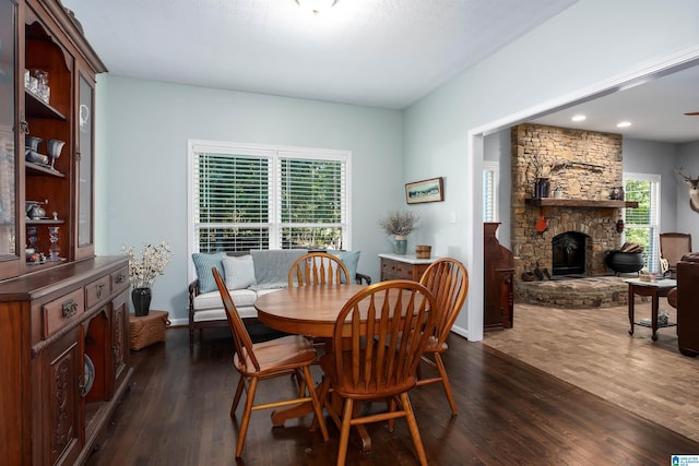 dining area with a fireplace, a healthy amount of sunlight, dark hardwood / wood-style floors, and ceiling fan