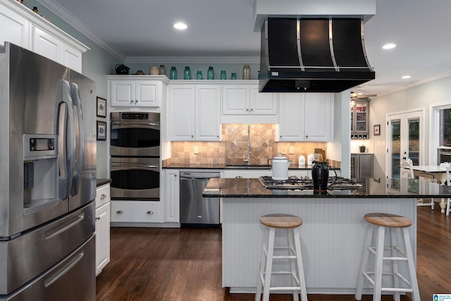 kitchen with stainless steel appliances, dark hardwood / wood-style flooring, ventilation hood, a breakfast bar, and white cabinetry